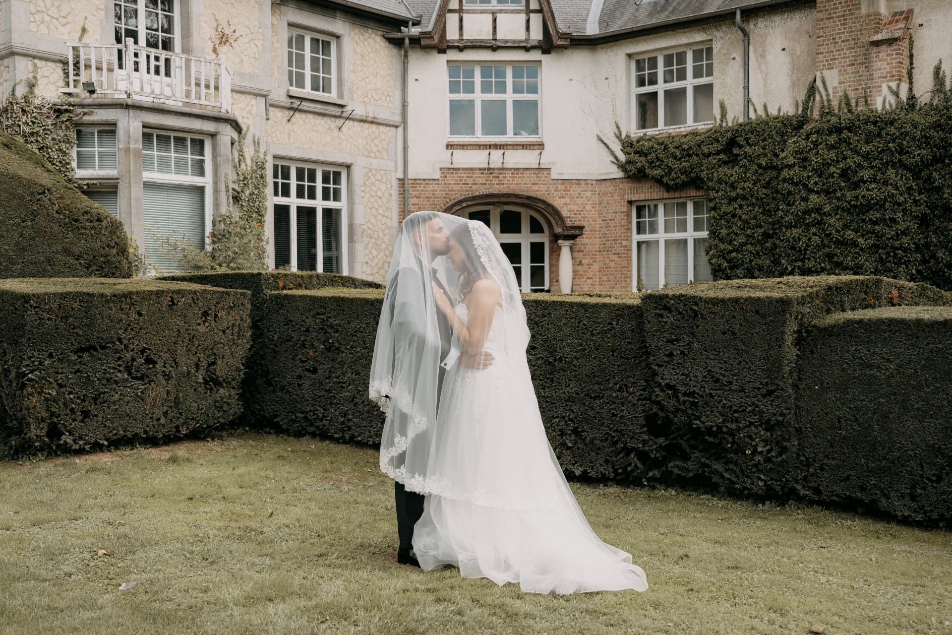 Les mariés sous le voile devant la maison