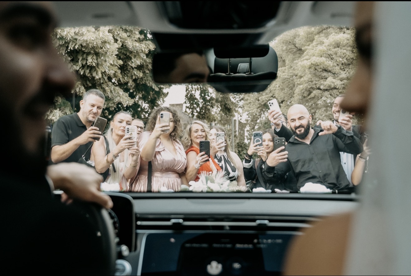 Les invités photographient les mariés à travers le pare-brise